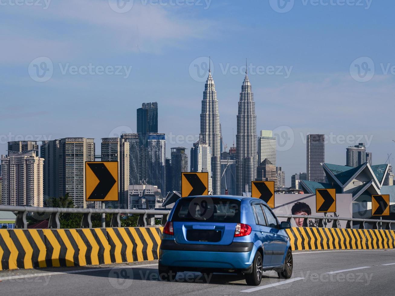 A small blue is driving her way into downtown Kuala Lumpur, Malaysia photo