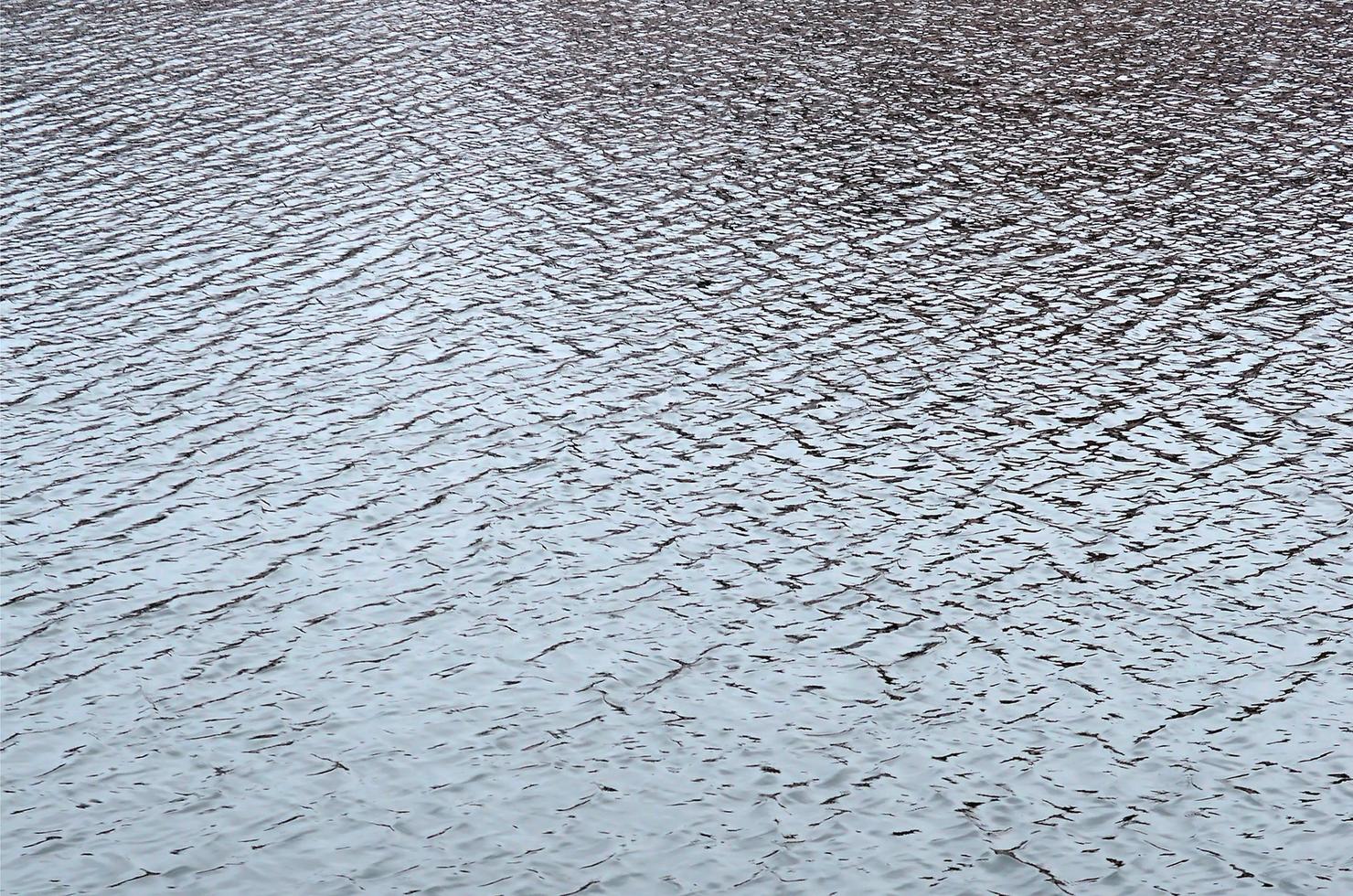 The texture of the water in the river under the influence of wind. A lot of shallow waves on the water surface photo