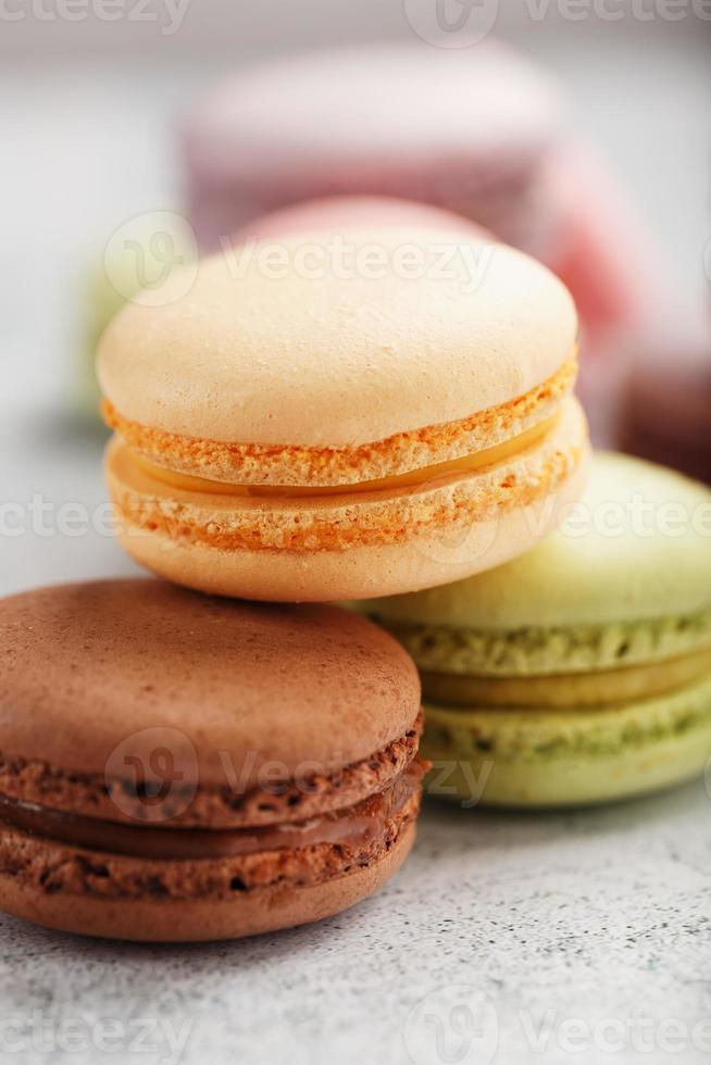 las galletas de macarrones franceses de diferentes colores están en la mesa gris. Bodegón de repostería. foto