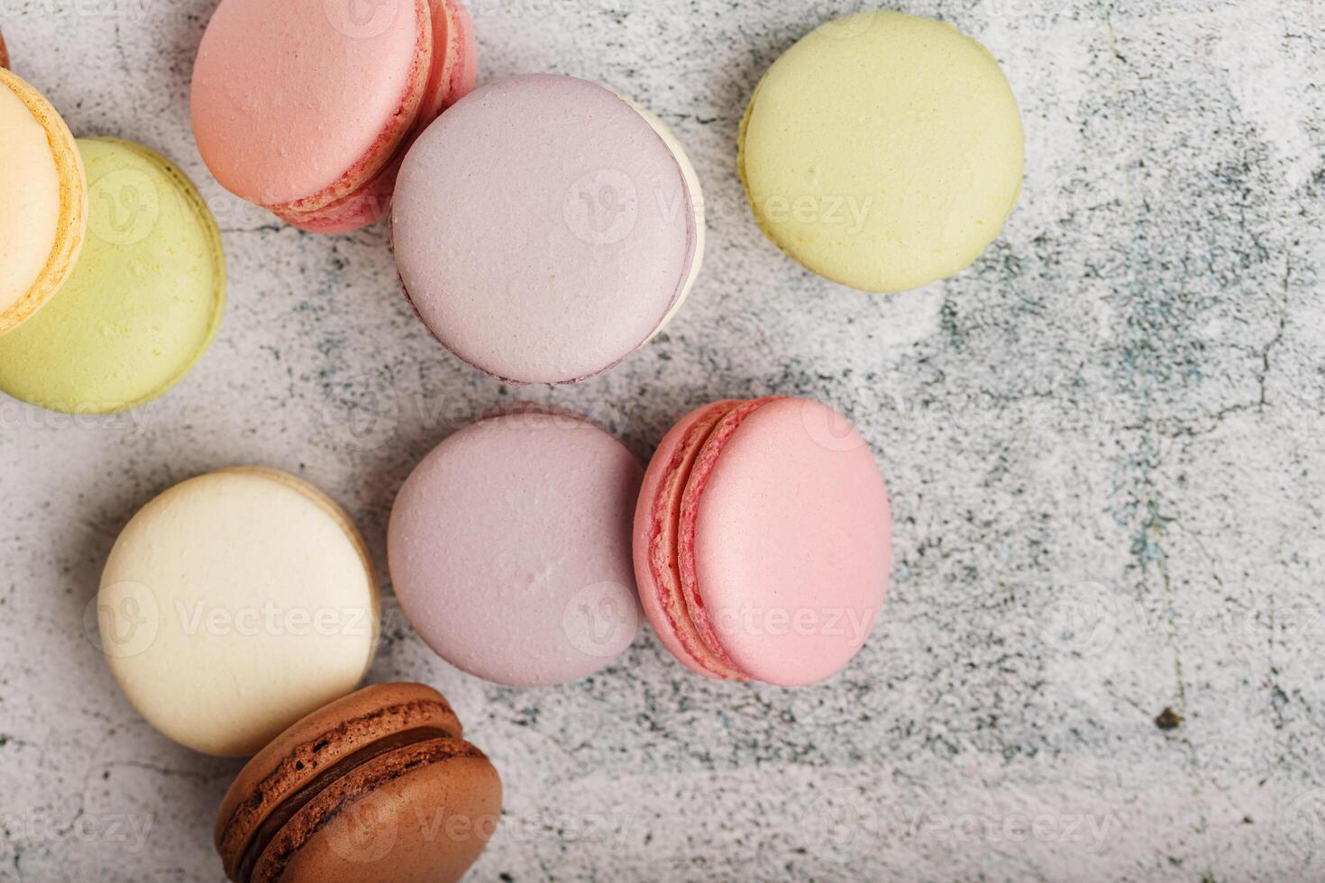 French macaroni cookies of different colors are on the gray table ...