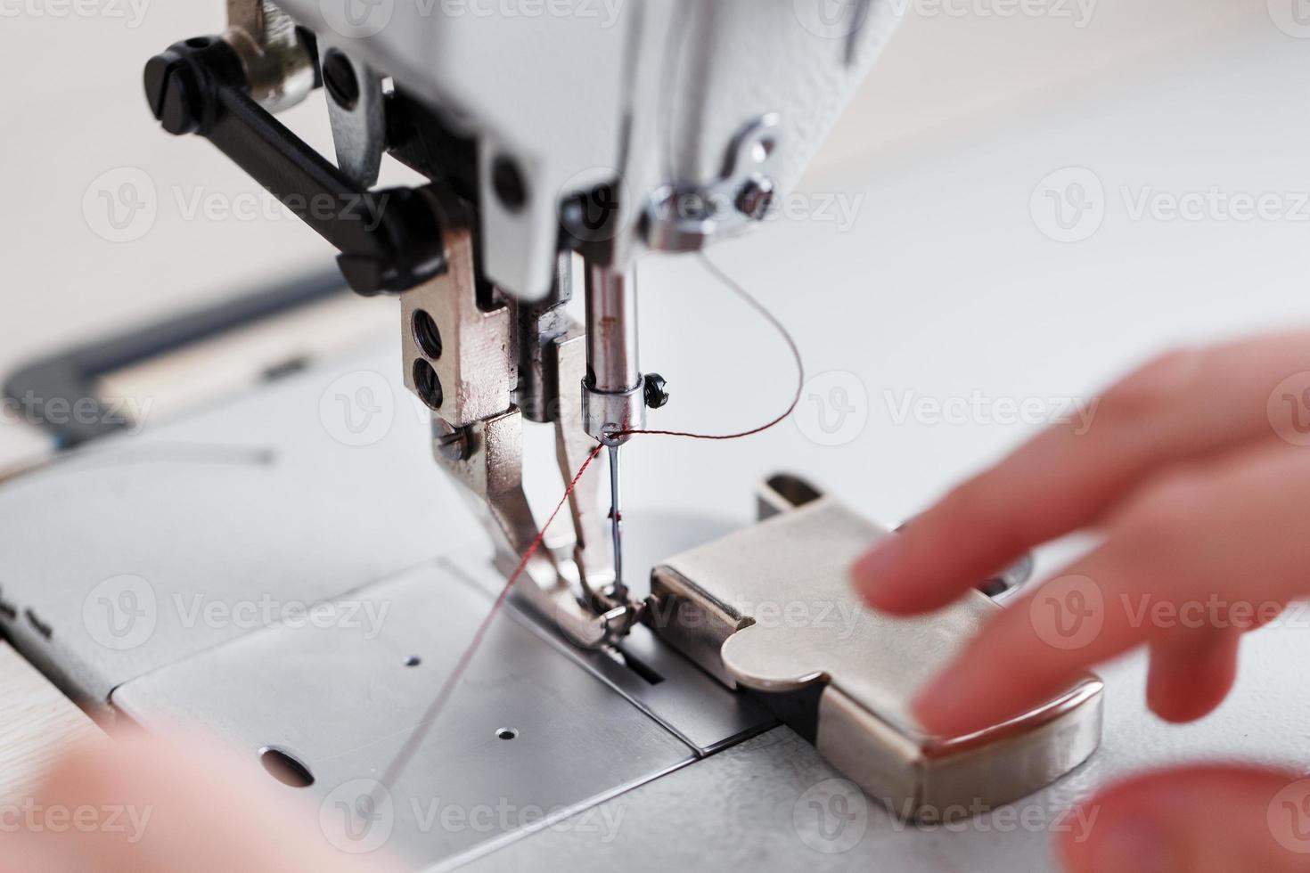 The hands of a master and the needle of a leather product sewing on a sewing machine. Manual work, business. photo