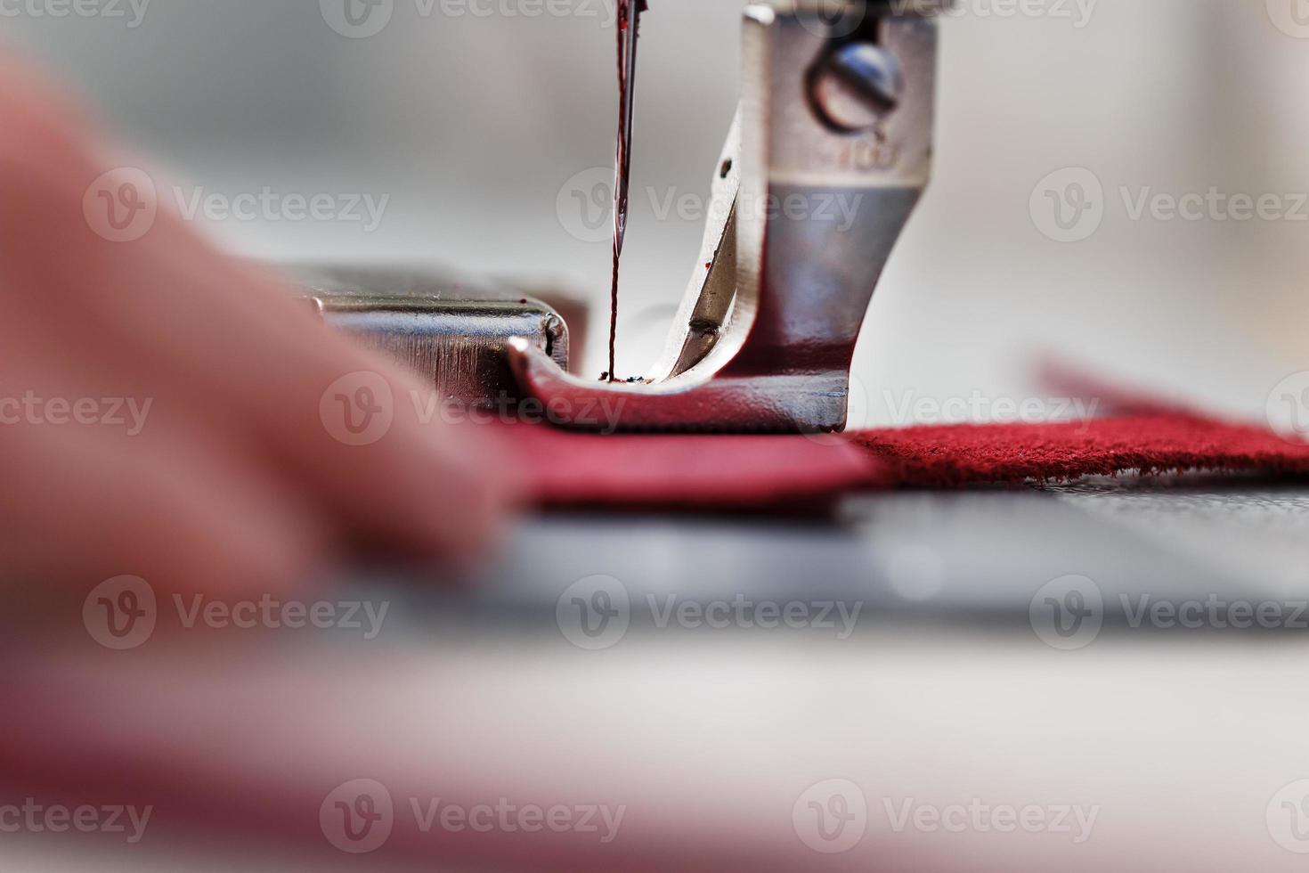 las manos de un maestro y la aguja de un producto de cuero cosiendo en una máquina de coser. trabajo manual, negocios. foto