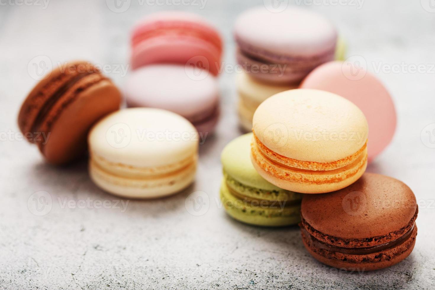 las galletas de macarrones franceses de diferentes colores están en la mesa gris. Bodegón de repostería. foto