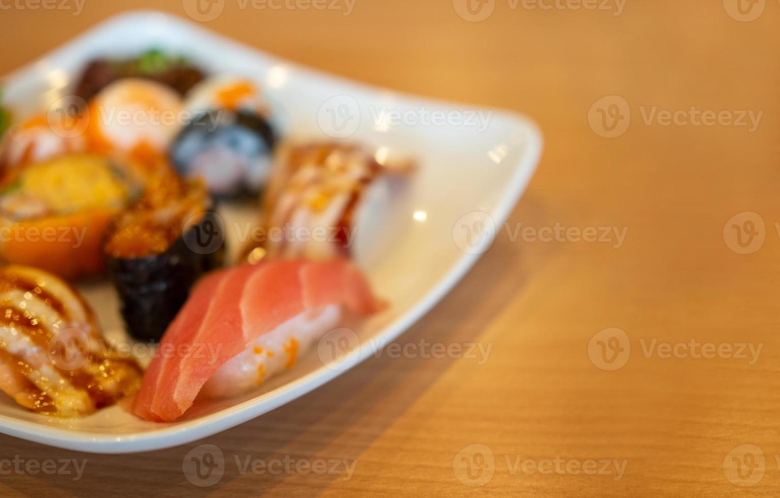 varios sushi en un plato blanco colocado sobre una mesa de madera foto