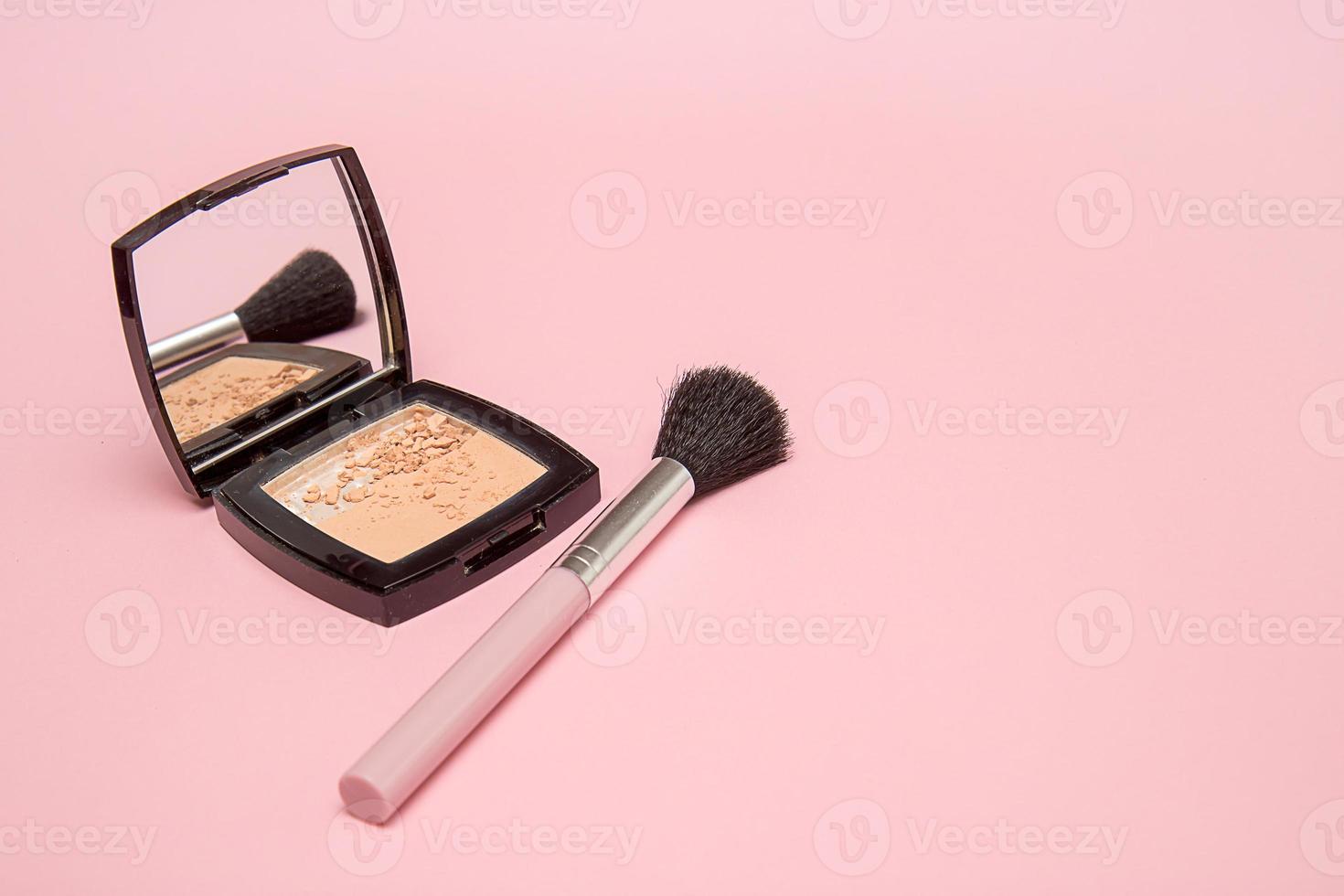 polvo y pincel de maquillaje sobre fondo rosa foto