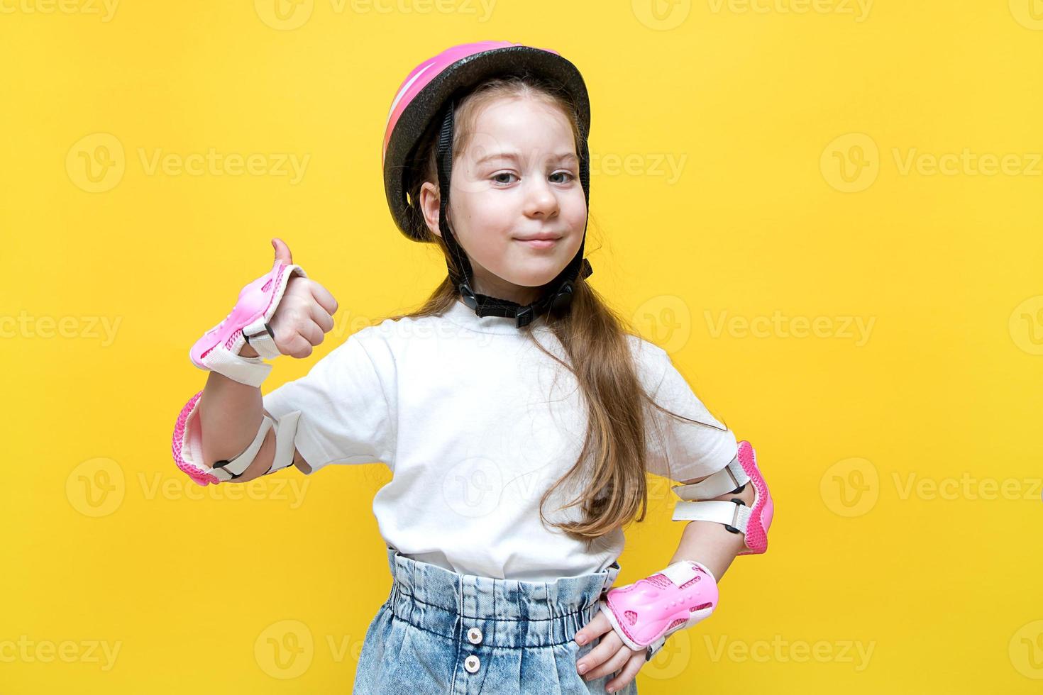 little girl in a protective helmet and elbow pads shows like photo