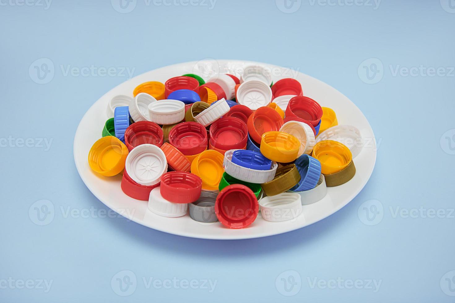 waste plastic lids in a white plate on a blue background, the concept of recycling, zero waste production photo