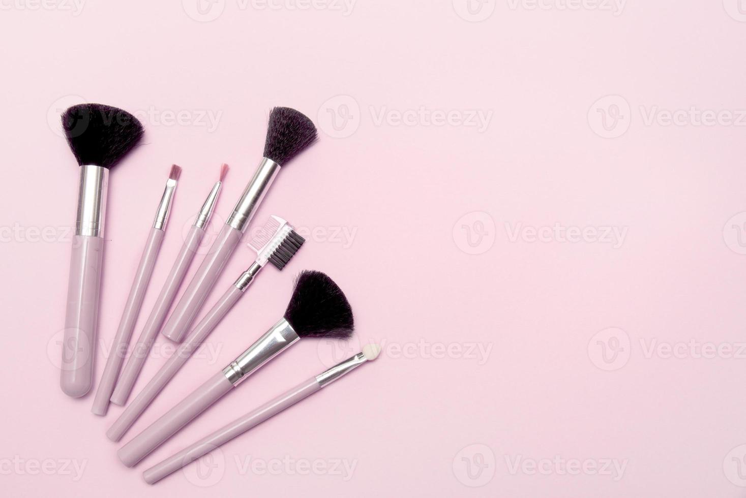 makeup brushes on pink background with copy space photo