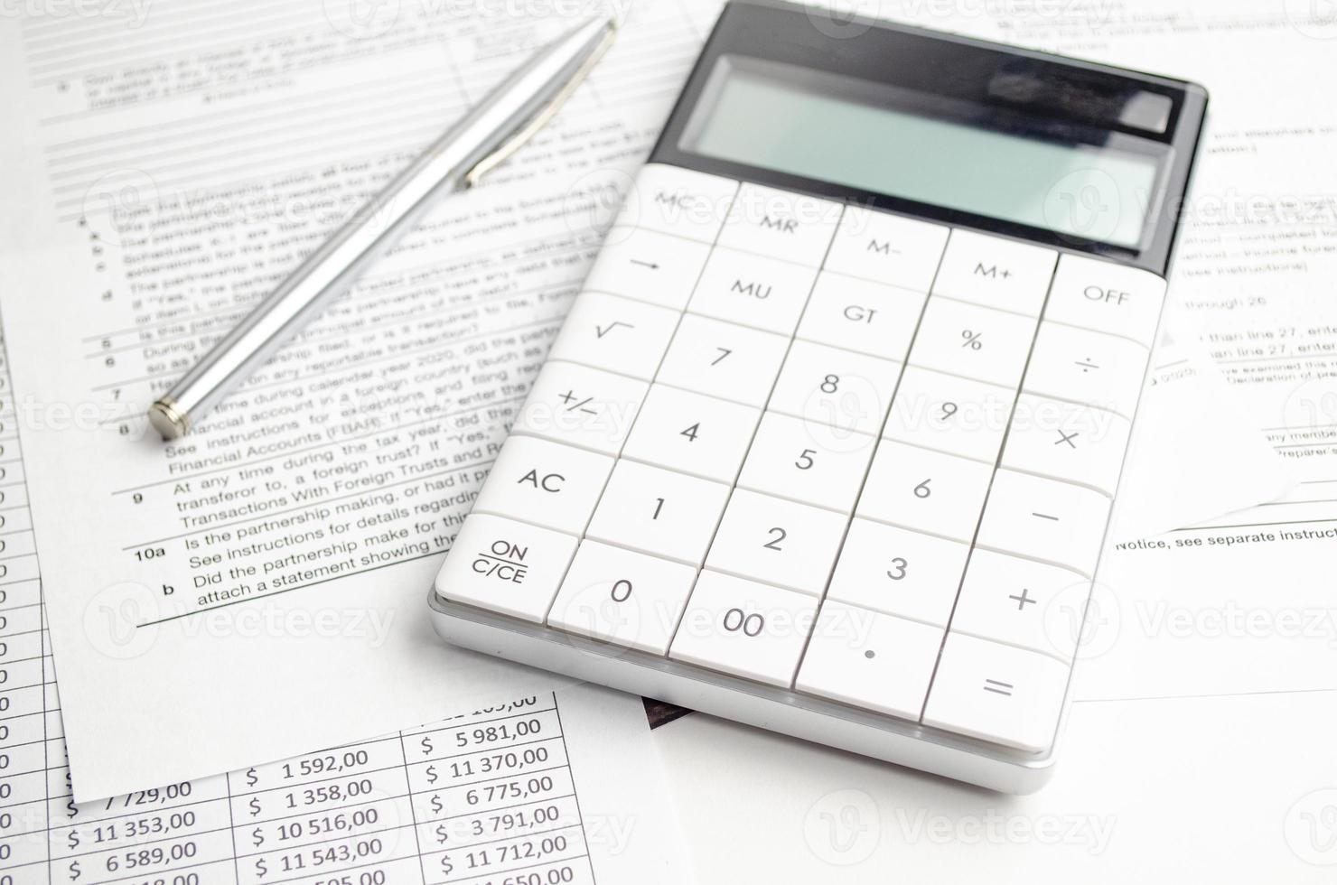 concepto de bolígrafo, calculadora y formularios de impuestos sobre fondo blanco foto
