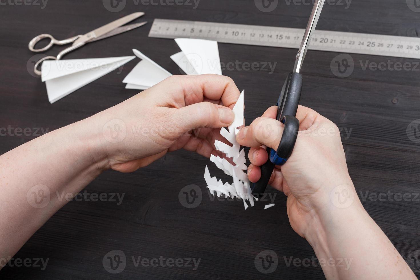 hand with scissors cut snowflake from paper photo