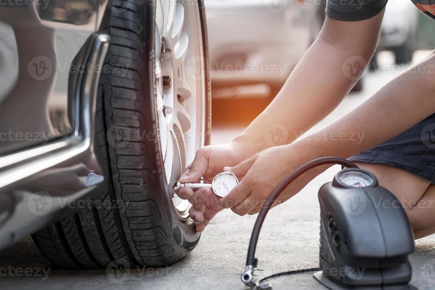 Asia man use Tire gauge analog check air pressure of wheel car on the road basic maintenance by oneself photo
