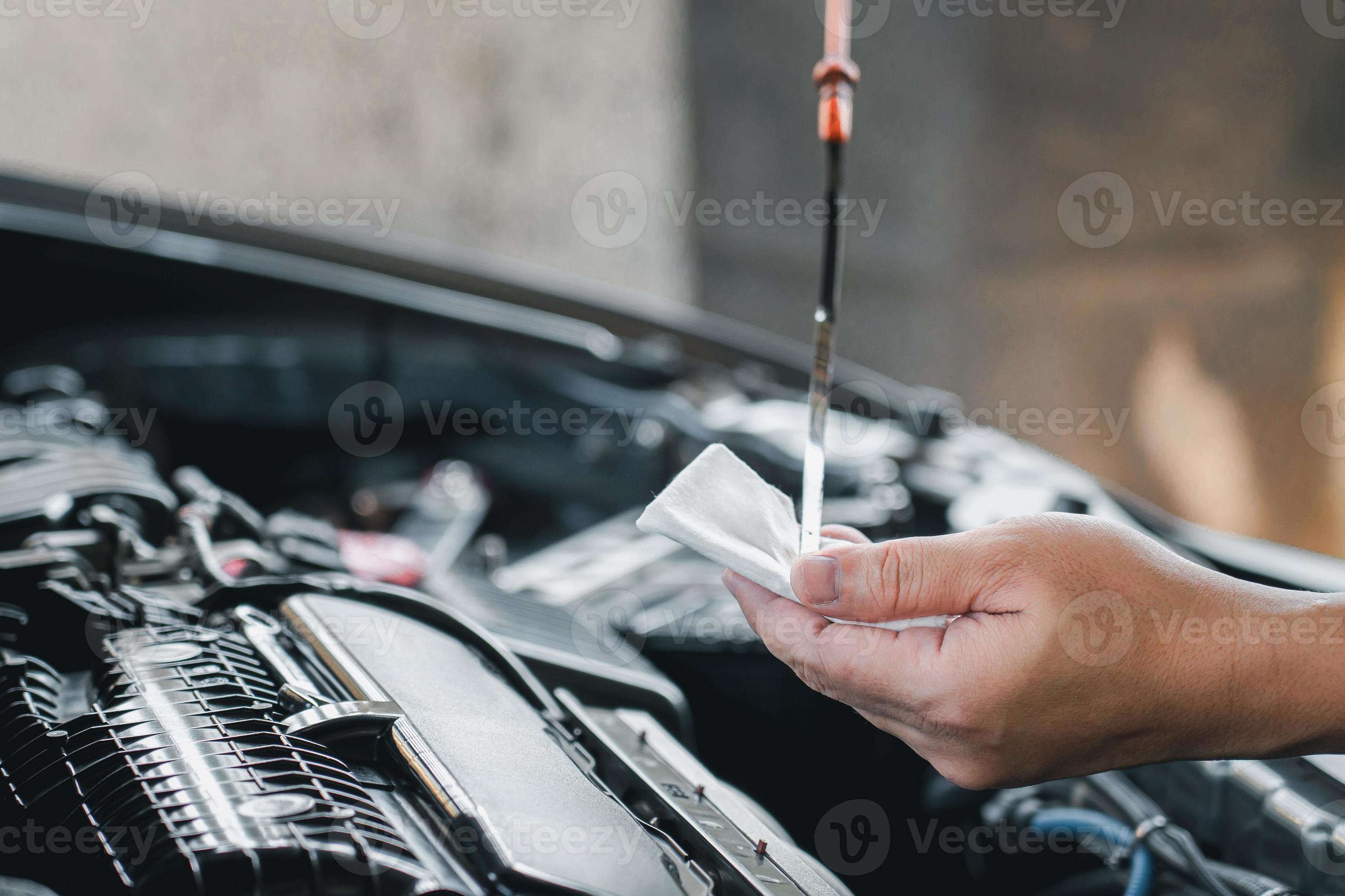 Man hold dipstick to check the engine oil level of engine and use white cloth clean oil dust in