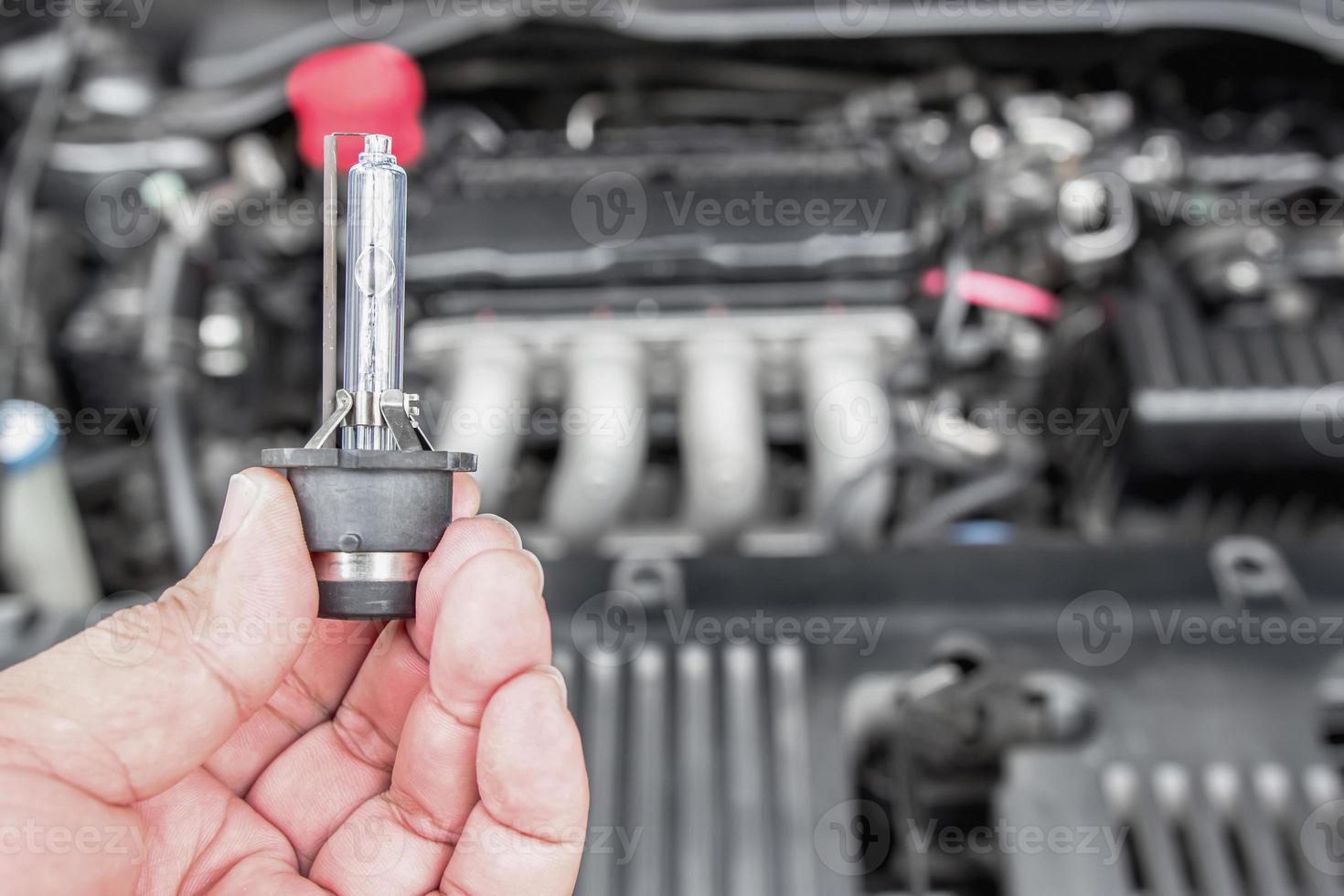 Close up car headlights xenon Lighting Equipment in hand a man with engine room for maintenance concept of car photo