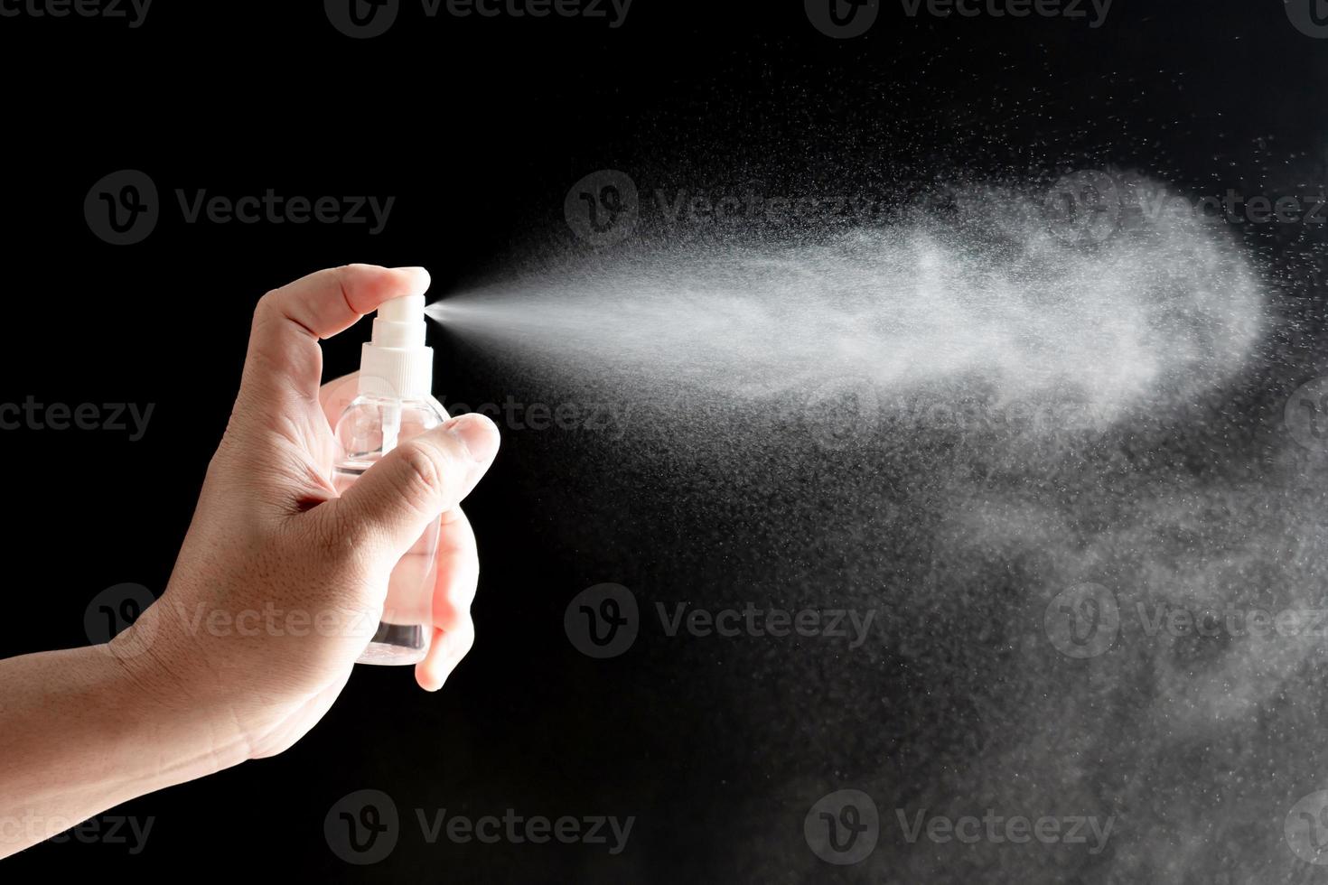 entregue a un hombre la botella de spray de alcohol para protección y virus pandémico de cuarentena, concepto de limpieza en fondo oscuro foto