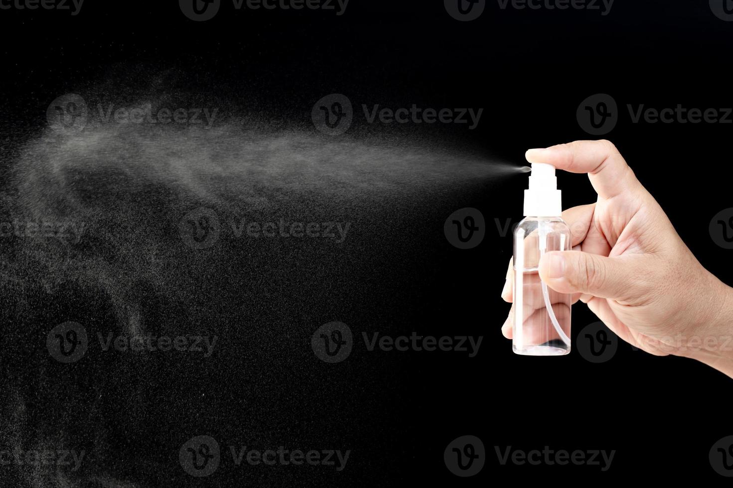 foto oscura concepto de mano un hombre presiona la botella de spray de alcohol para limpieza de protección y limpieza de virus pandémico de cuarentena