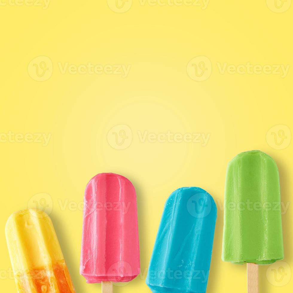 Colorful ice cream popsicles on yellow background, top view photo