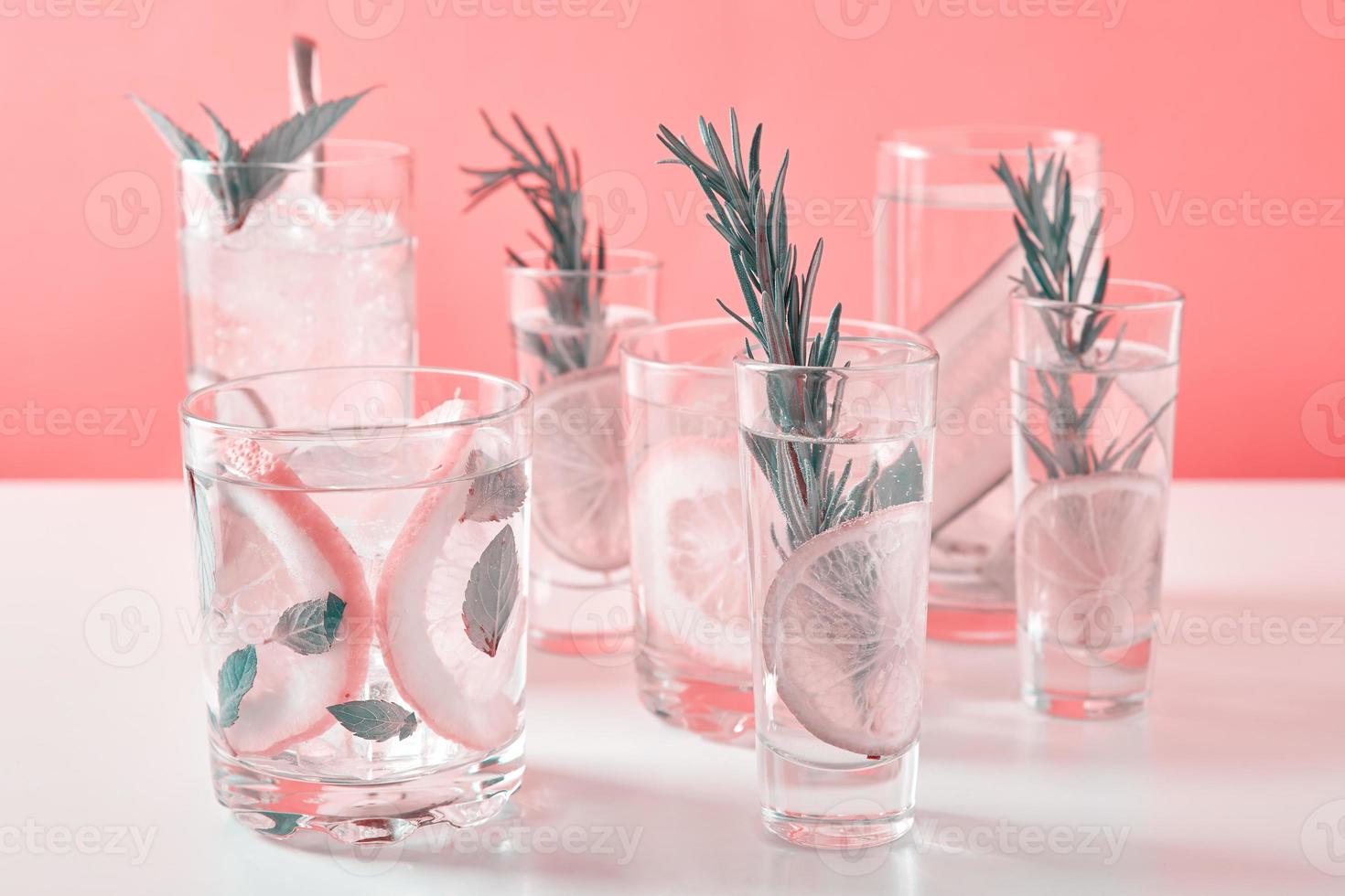 bebida con lima y romero sobre fondo rosa foto