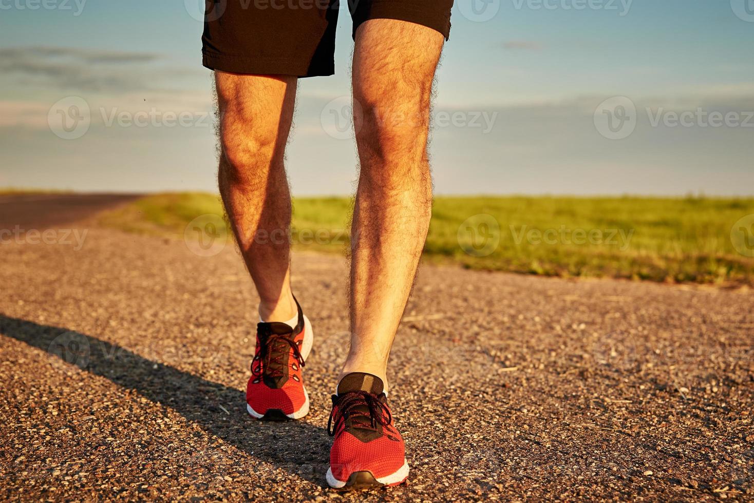 Runner man feet on road at the sunset photo