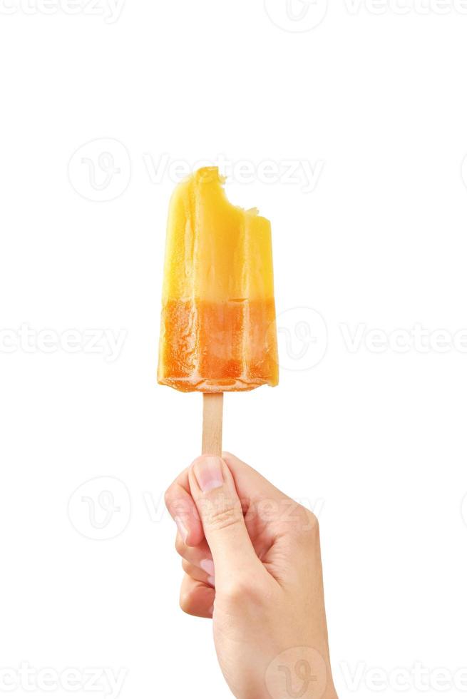 Bitten yellow frozen fruit ice cream popsicle in woman hand on white background photo