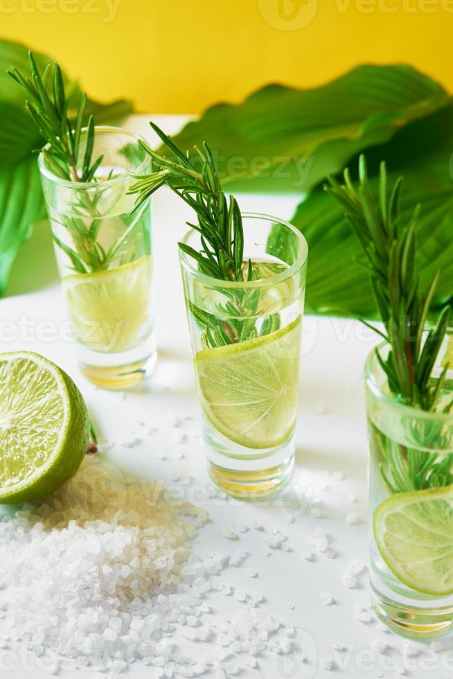 Drink with lime and rosemary on yellow background photo