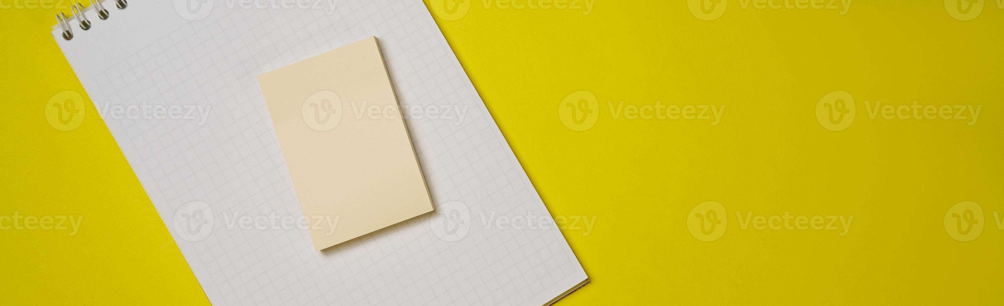 abra el bloc de notas blanco en blanco en una espiral y pegatinas en un fondo amarillo. foto