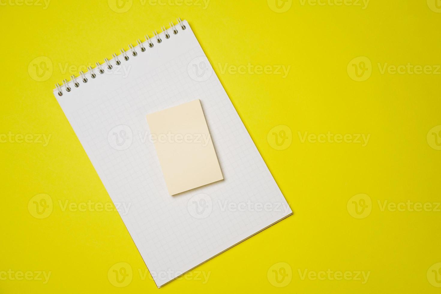 Open blank white notepad on a spiral and stickers on a yellow background. photo