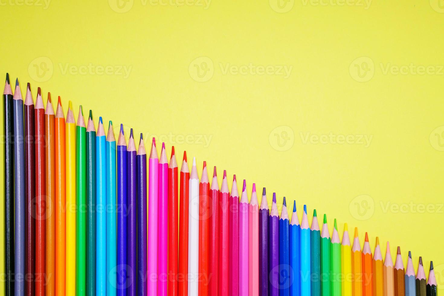 Many different colored pencils on a yellow background. Place your text. photo