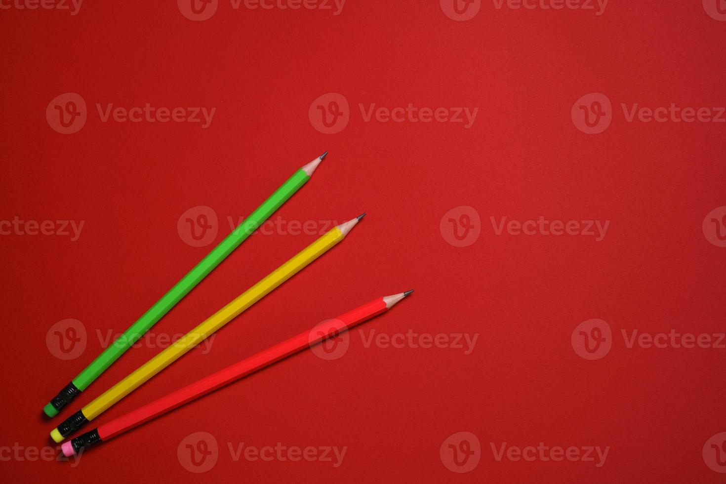 Colored wooden pencils on red background, education concept. photo