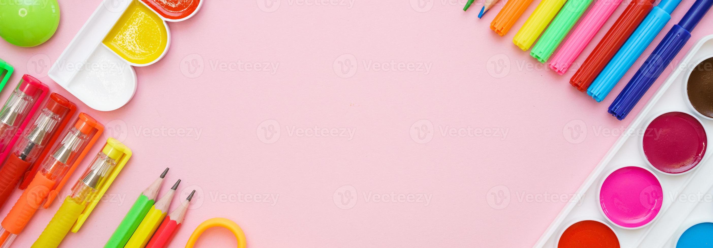 School stationery colorful paint pencils and pens on pink background in form photo