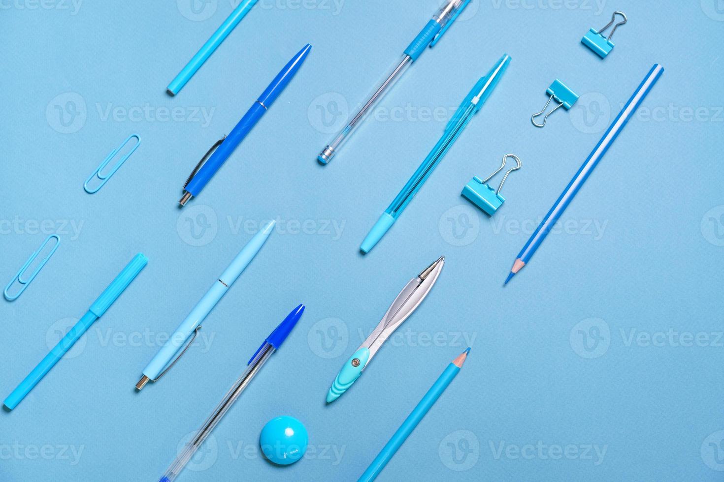 Pens pencils compasses paper clips laid out in lines all blue and background photo
