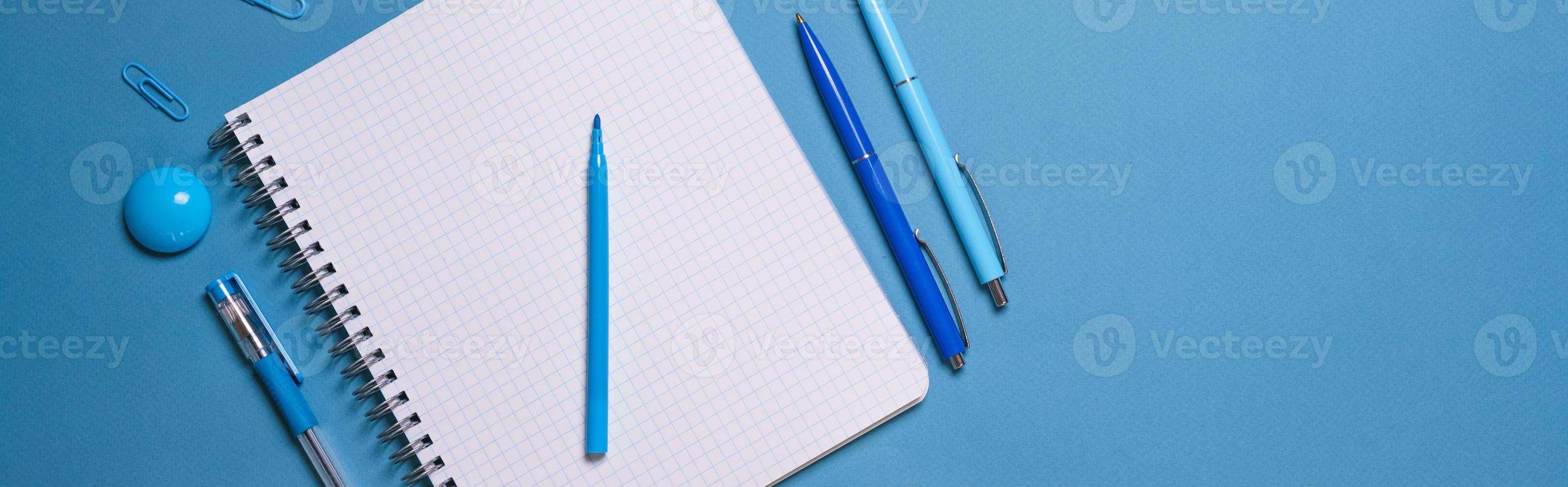 Notebook and pen on a blue background. Top view with copy space. Stationery photo