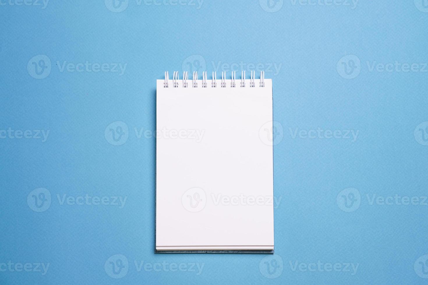 School notebook on blue background, spiral notepad on table, education photo