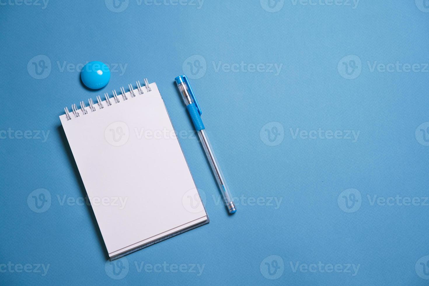 Notebook and pen on a blue background. Top view with copy space. Stationery photo