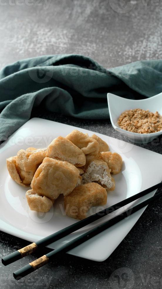 Fried tofu served in a white plate with tamarind sauce and mashed beans, fried tofu is a popular dish among Chinese and Asians. photo