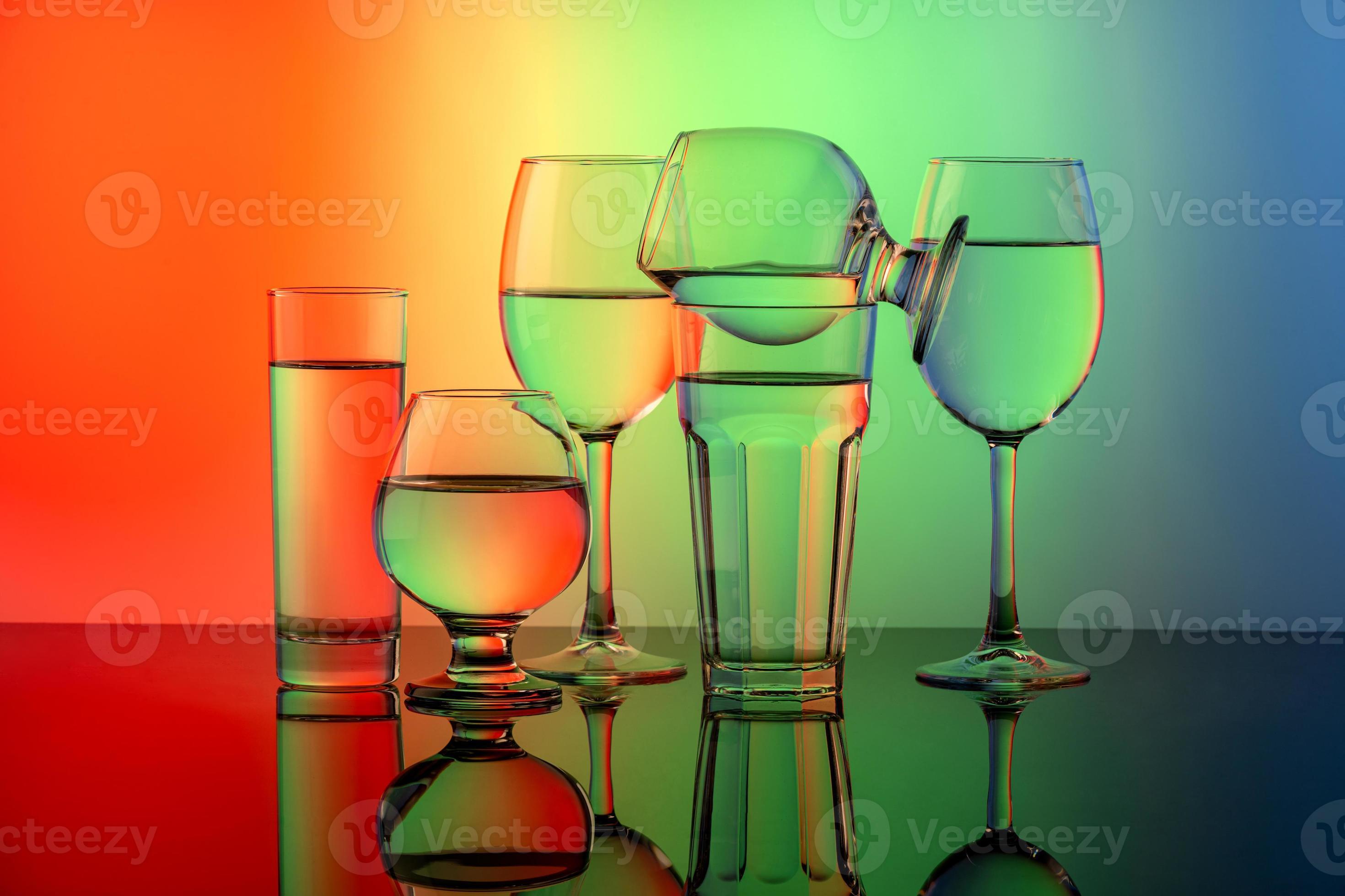 Some glasses for different drinks stacked on a colorful background