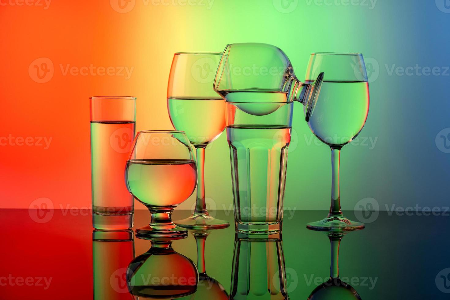 Some glasses for different drinks stacked on a colorful background photo