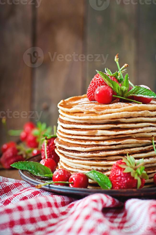 Pancakes with berries and syrup in a rustic style photo