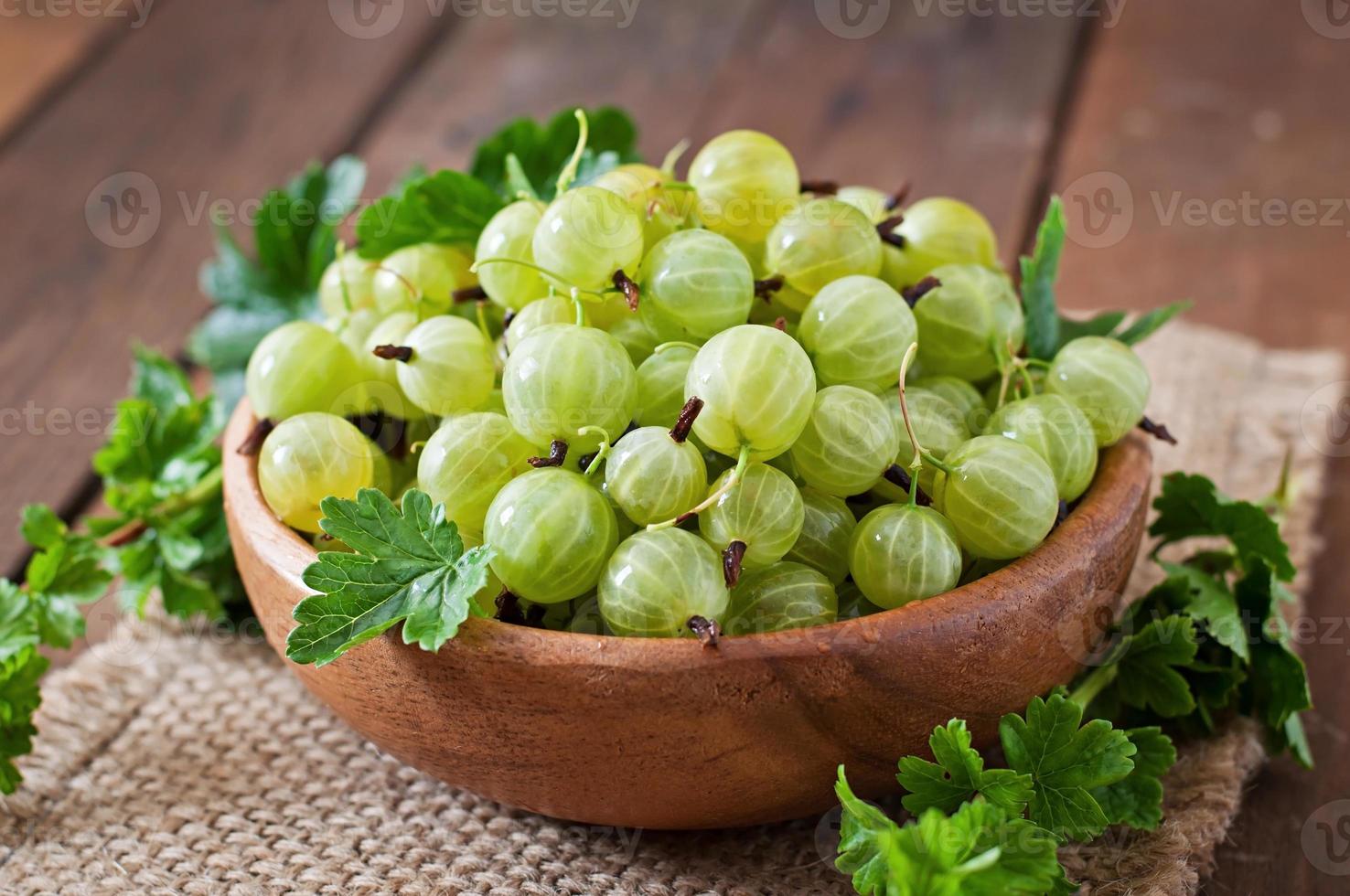 Green gooseberries in a wooden bowl photo