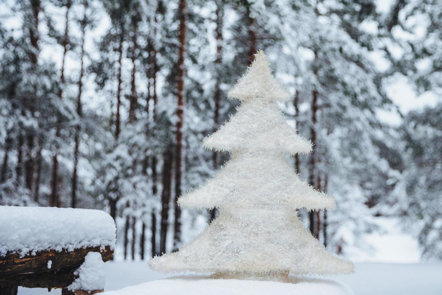 White artificial fir tree stands on wooden branch, covered with snow. Christmas or New Year decor. Season concept. Beautiful winter landscapes. Frosty weather photo