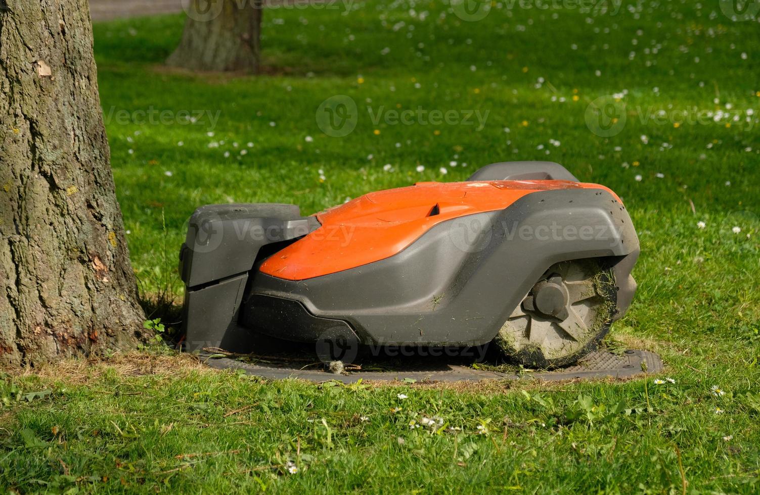 Robotic Lawn Mower on green grass background.Automatic robot lawnmower in modern garden.Green grass trimming with lawn mower. Close-up view of the lawn mower dirty blade after mowing the lawn. photo