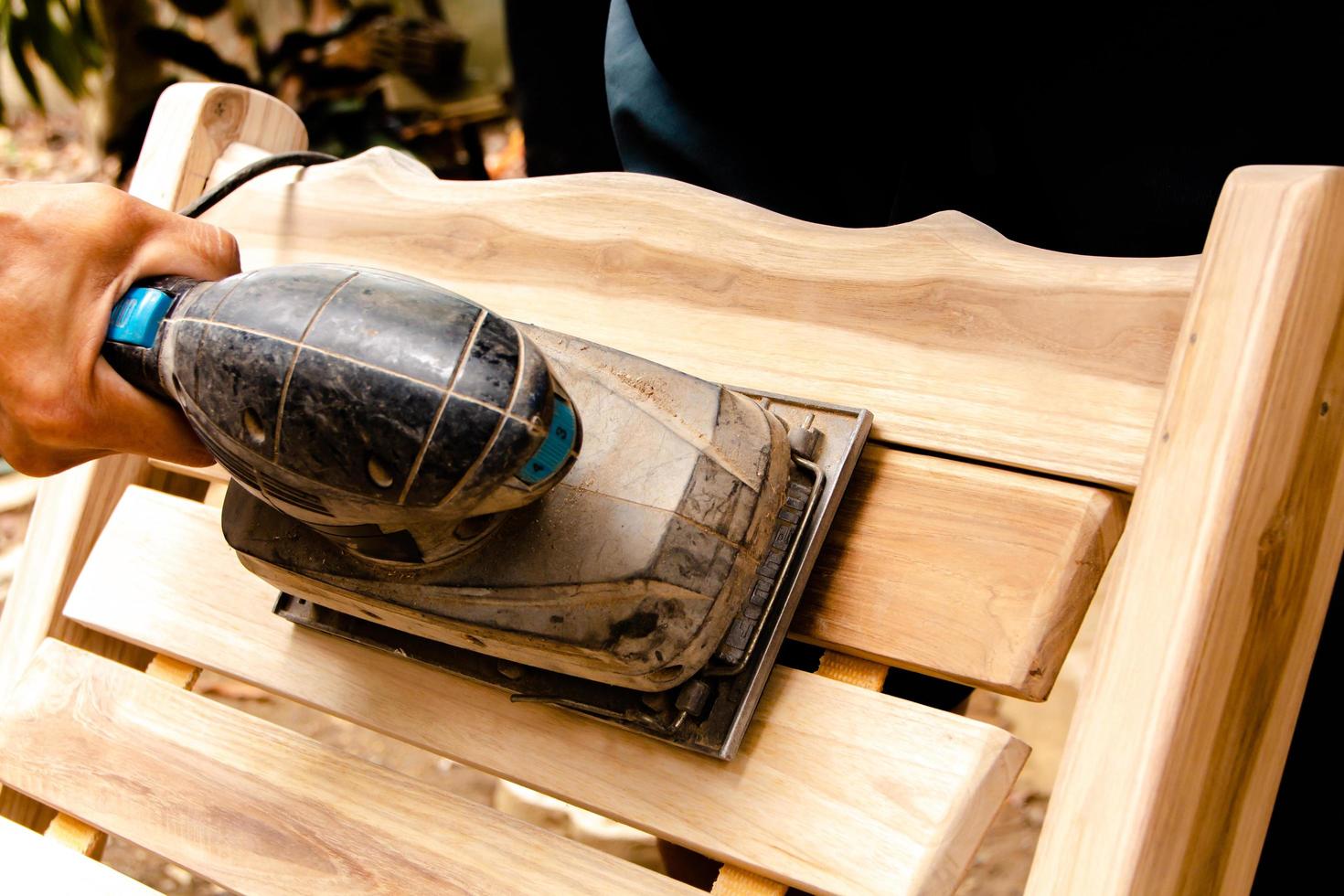 Sanding the teak furniture smooth and clean with a sander. photo