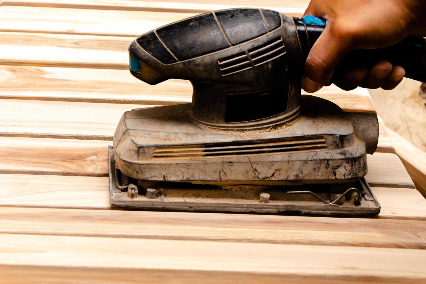 Sanding the teak furniture smooth and clean with a sander. photo