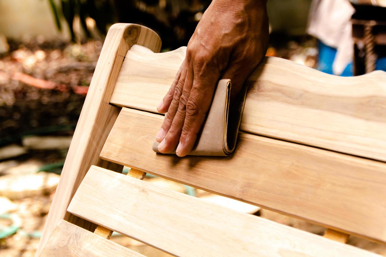 trabajando para alisar la madera y limpiar con papel de lija foto