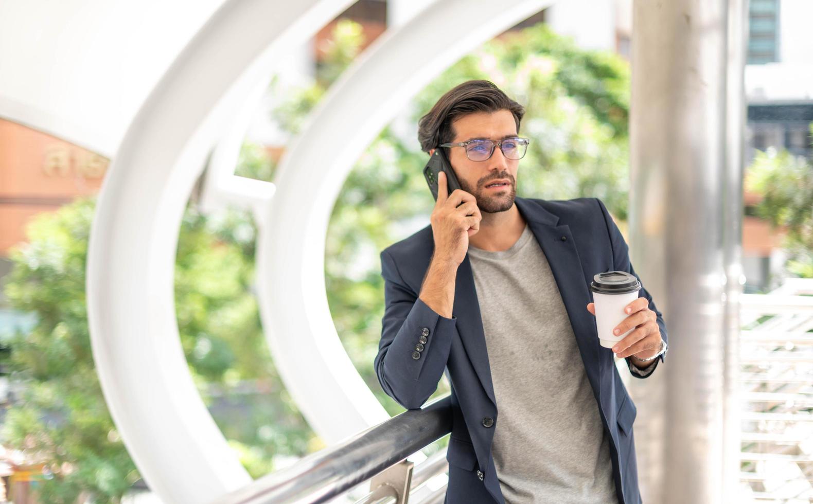 The man holding a cup of coffee and using a smartphone and talking with his friend while he waiting his friend at the airport. photo