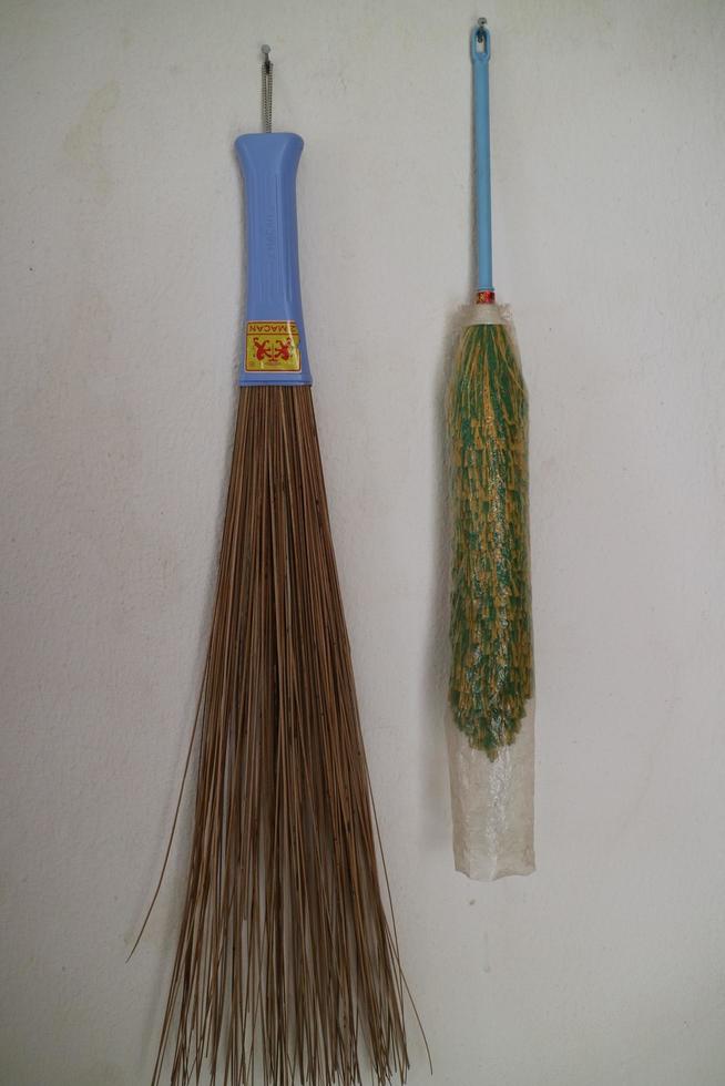 duster and broom stick hanging on the wall of the house photo