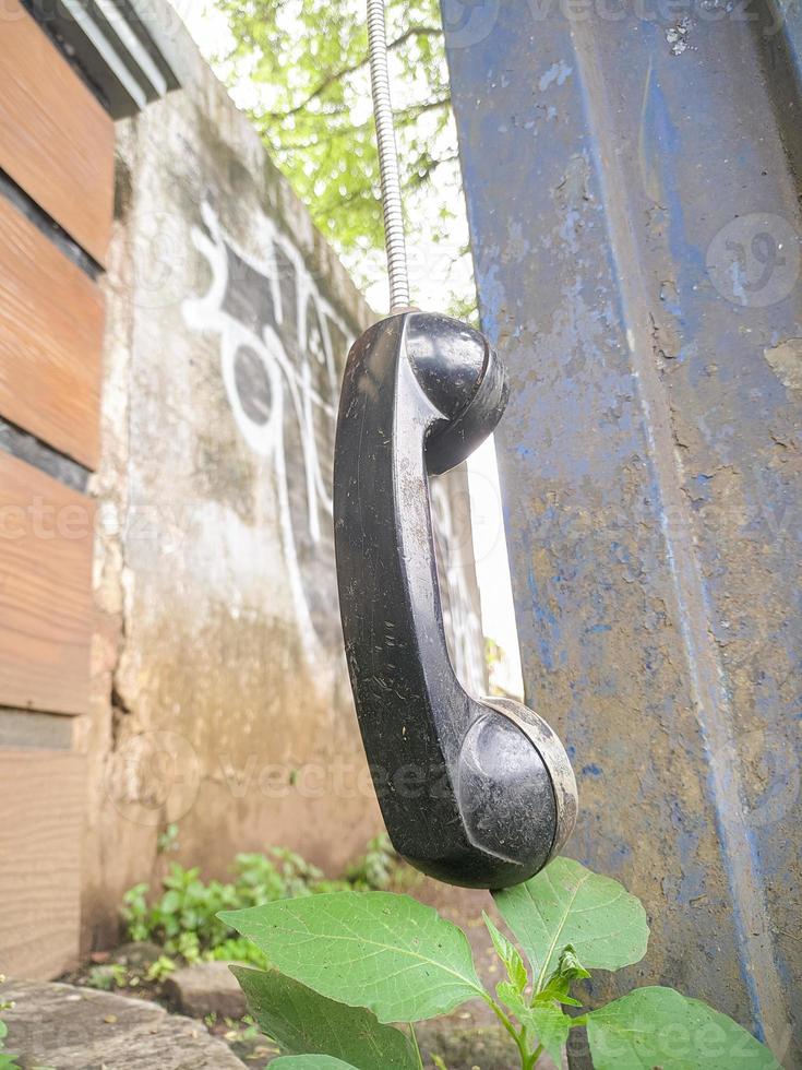 an old type of telephone handle isolated in an abandoned park. a type of telephone era in 1990 photo