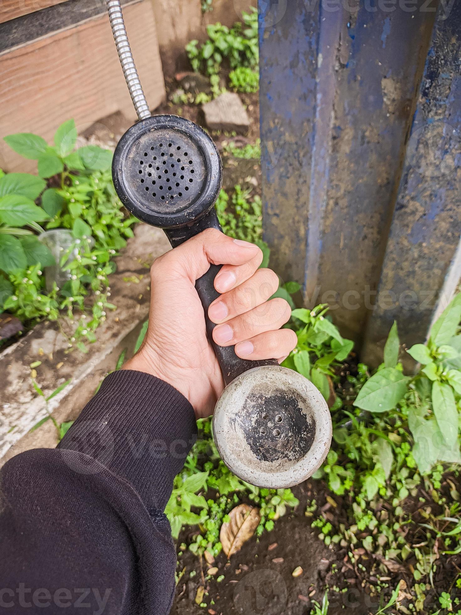 an old kind of telephone handle that is isolated with a man's hand. a