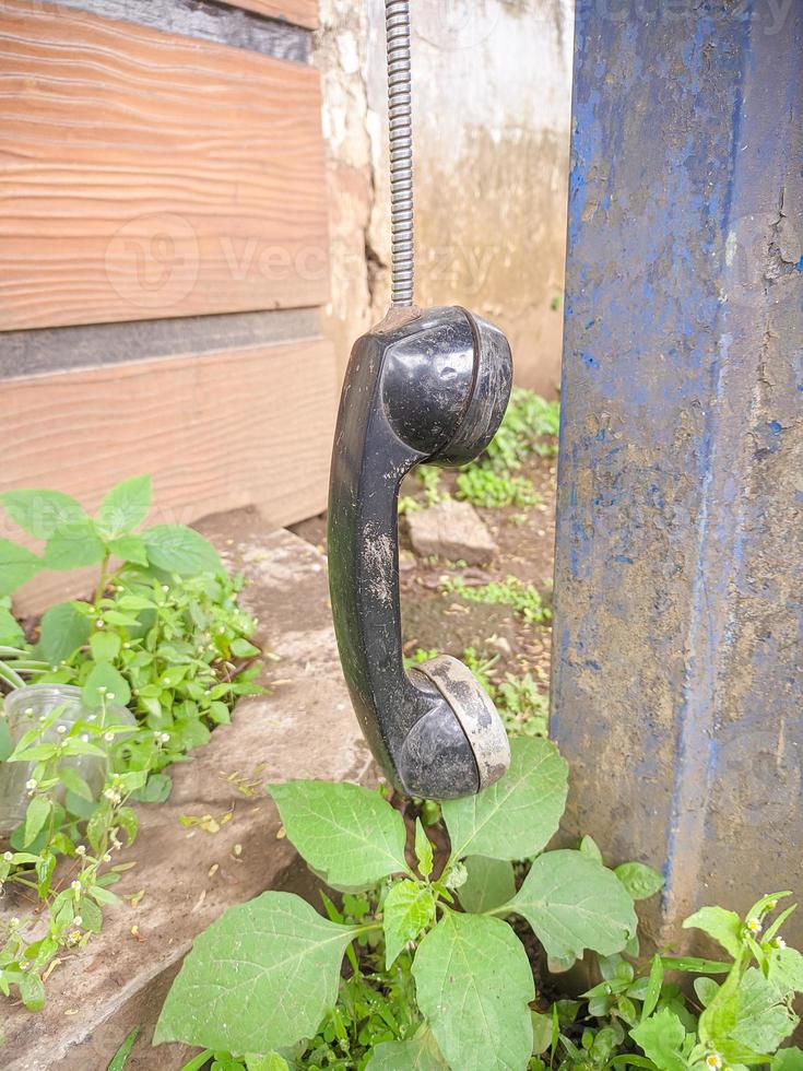 an old type of telephone handle isolated in an abandoned park. a type of telephone era in 1990 photo