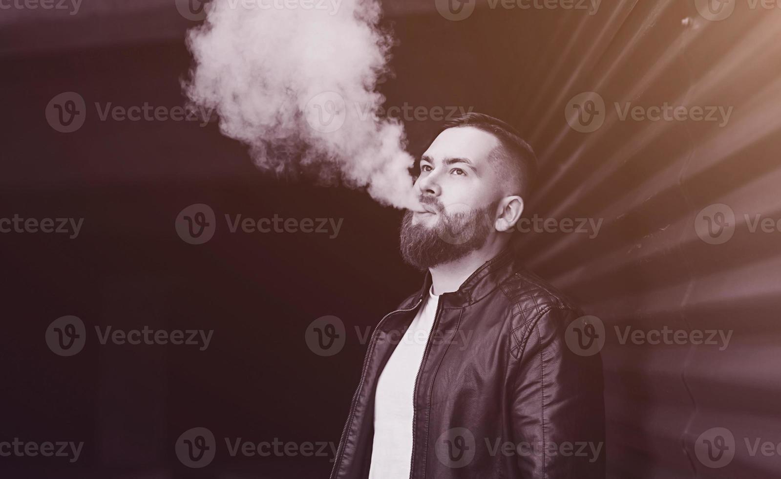 hombre guapo en un vapeo de un cigarrillo electrónico foto