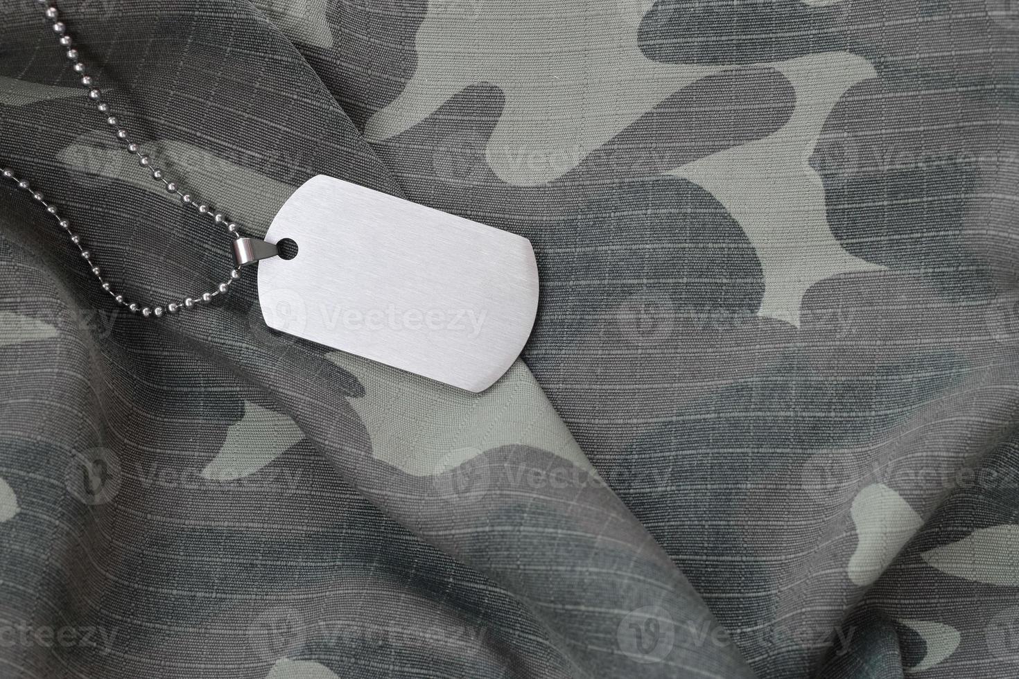 Silvery military beads with dog tag on camouflage fatigue uniform photo